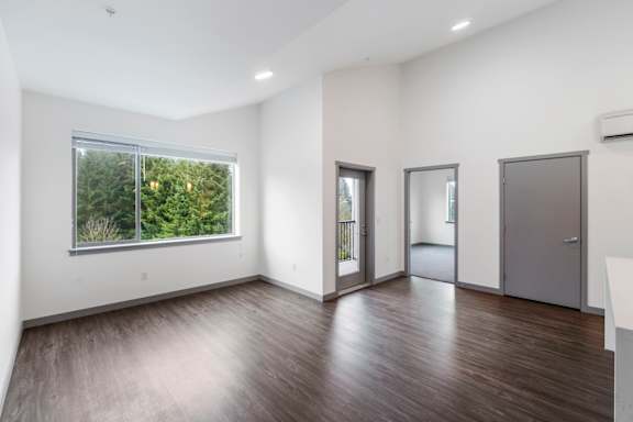 A spacious room with wood flooring and a large window.