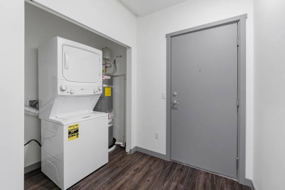 A small white fridge in a room with a grey door.