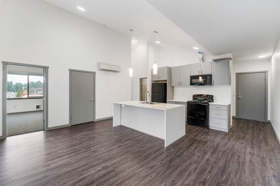 A spacious kitchen with a white island and dark wood flooring.