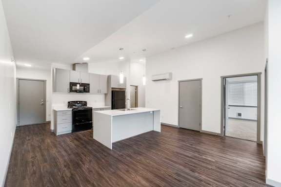 A modern kitchen with a white island and dark wood floors.