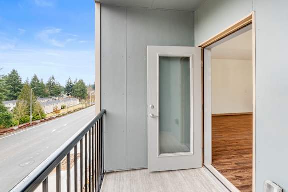 A balcony with a glass door and a wooden floor.