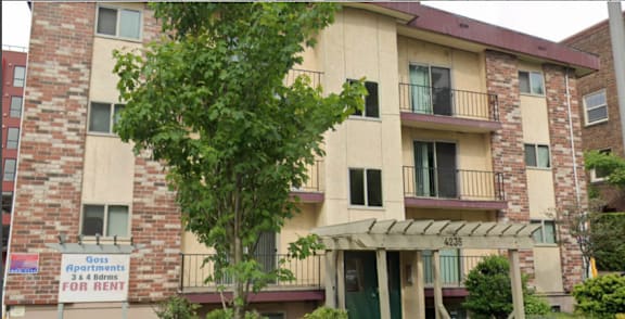 Apartment building with a sign that says "Goss Apartments for Rent".