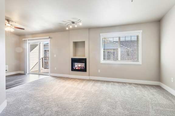 A spacious living room with a fireplace and a ceiling fan.