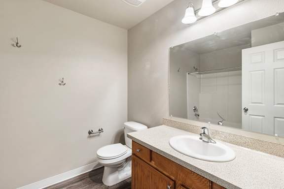 A bathroom with a toilet, sink, and mirror.