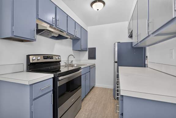 A kitchen with blue cabinets and white countertops.
