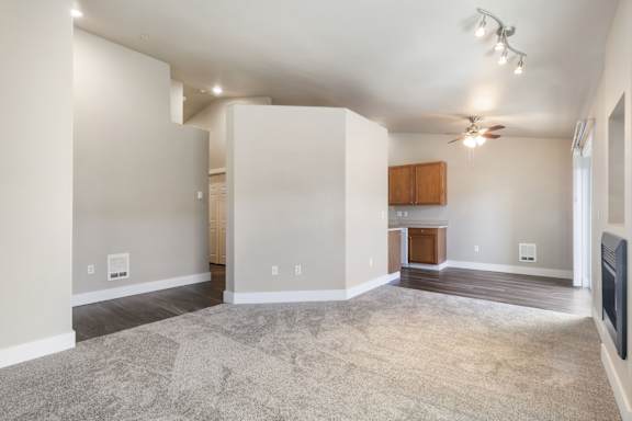 A spacious living room with a ceiling fan and a fireplace.