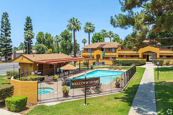 A yellow building with a pool in front and a sign that says "Welcome Home".