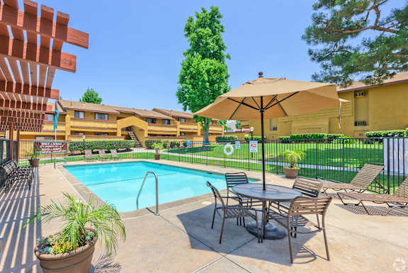 A pool area with a table and chairs and a patio umbrella.