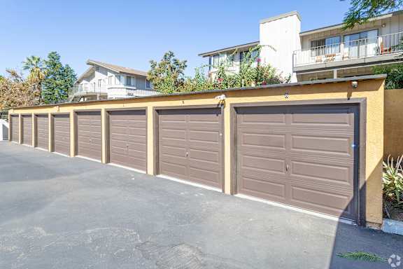 A row of brown garage doors in front of a building.