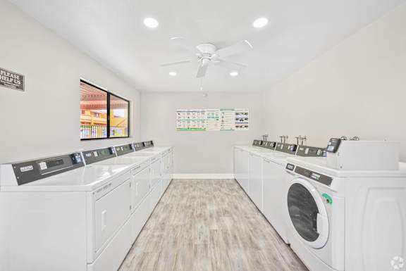 A laundry room with a row of washers and dryers.