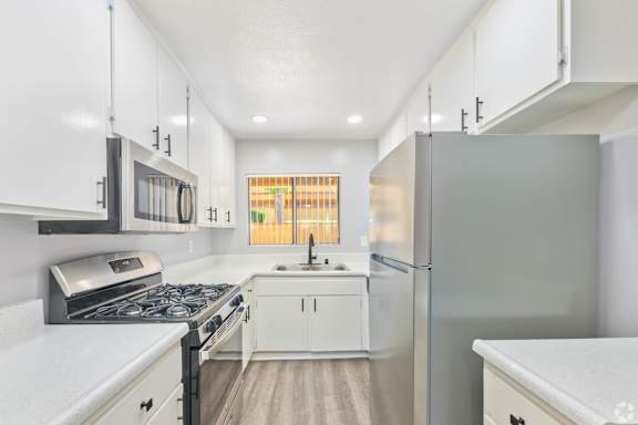 A modern kitchen with white cabinets and stainless steel appliances.
