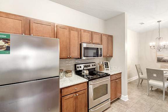 Kitchen with a stainless steel refrigerator, microwave, oven, and a dining table with chairs at Highlands Apartment Homes, Tennessee