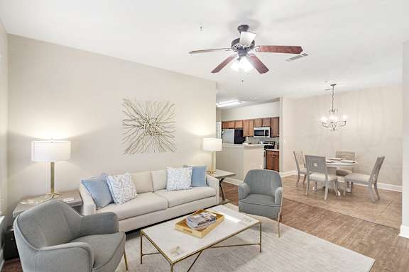 Living room with a white couch, a coffee table, and a ceiling fan with hardwood floors at Highlands Apartment Homes, Bartlett, Tennessee