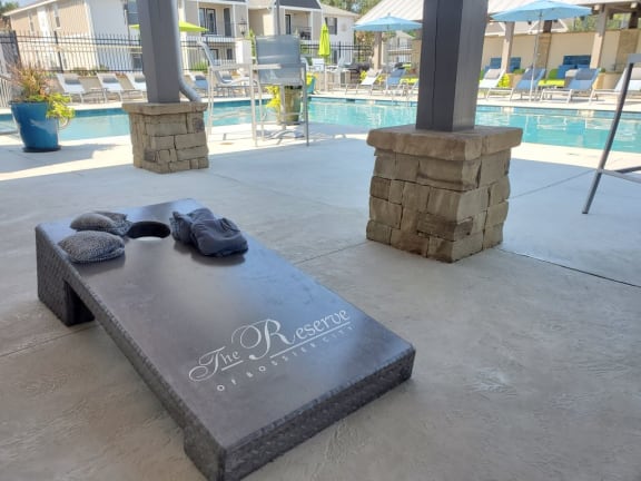 a stone bench with towels on it and a pool in the background at Reserve of Bossier City Apartment Homes, Louisiana,