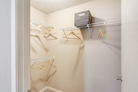 A white closet with a shelf and hangers at Avalon Apartment Homes in Starkville, Mississippi 39759