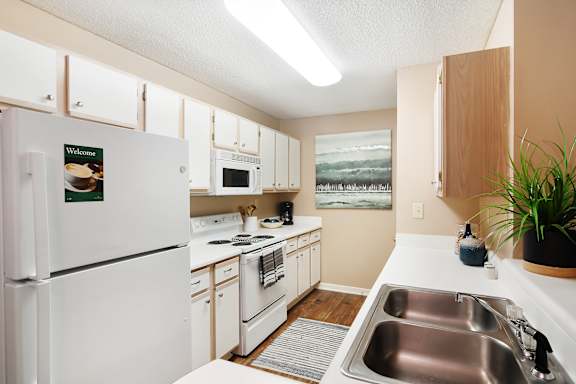 A kitchen with a white refrigerator and a sink and microwave Lexington Pointe Apartment Homes in Oxford, MS 38655