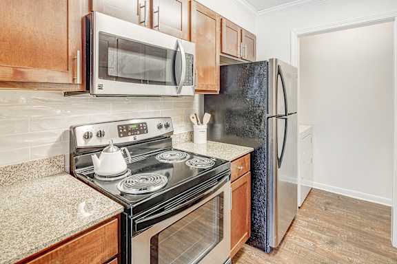 A kitchen with a black stove top oven and a black refrigerator at Cambridge Station Apartment Homes in Oxford, MS