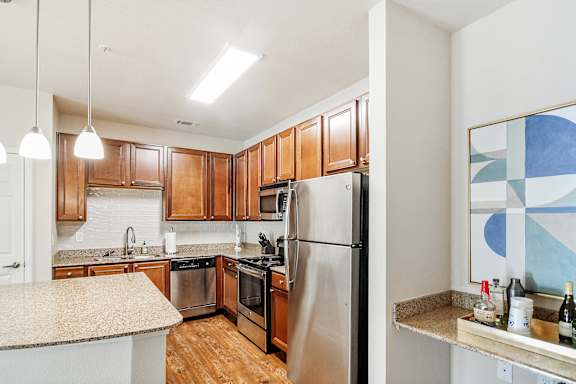 Kitchen with wooden cabinets and a stainless steel refrigerator at Faulkner Flats Apartment Homes, Oxford, MS, Mississippi&#xA0;, 38655