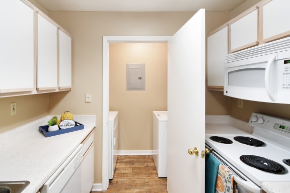 a kitchen with white appliances and white cabinets      and a door  at Parklane Apartment Homes, McComb, Mississippi