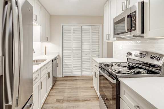A modern kitchen with white cabinets and stainless steel appliances at The Oliver Apartment Homes in Olive Branch, MS