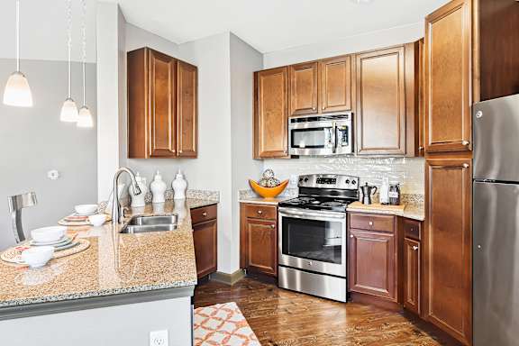 A kitchen with wooden cabinets and a granite countertop at Wellington Grande Apartment Homes, Longview, TX, 75605