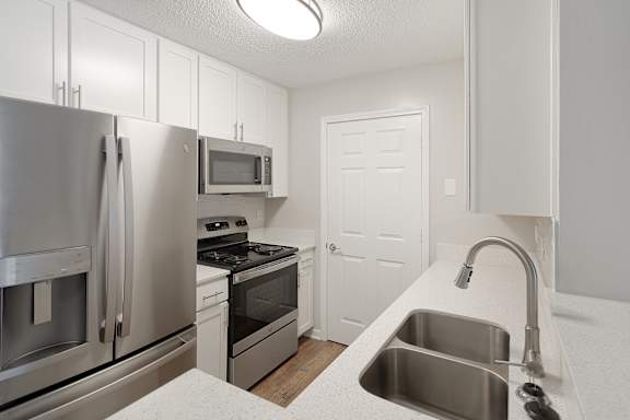 a kitchen with stainless steel appliances and white cabinets at The Woodlands Apartment Homes, Meridian, MS, 39301