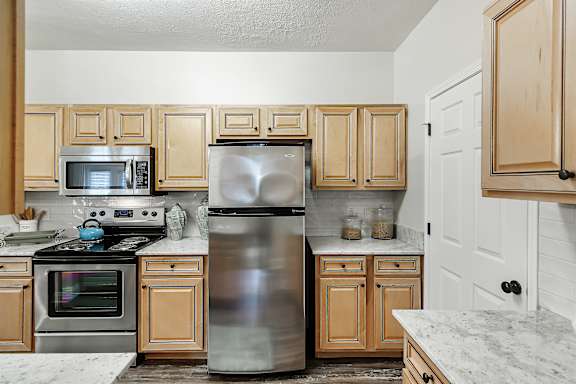 a kitchen with stainless steel appliances and wooden cabinets at Charleston Apartment Homes, Mobile, 36695