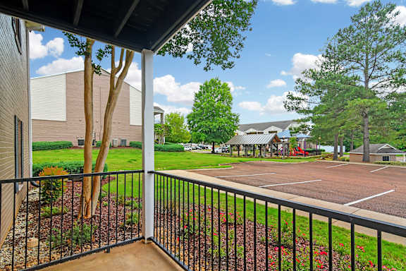 A view from a balcony looking out at a parking lot and trees at Highpointe Apartment Homes, Mississippi  , 39042