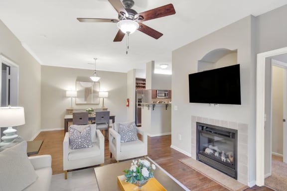 a living room with a fireplace and a ceiling fan at Ashford Place Apartment Homes, Flowood, MS, 39232