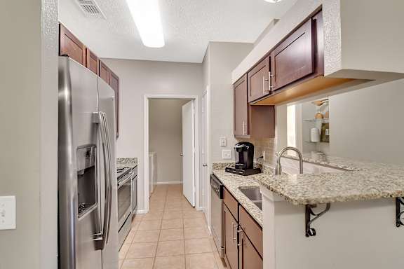 A kitchen with a refrigerator, sink, and cabinets at Ashford Place Apartment Homes, Mississippi 39232