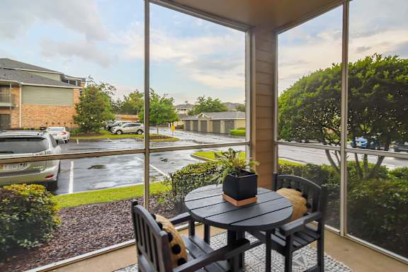 a patio with a table and chairs and a large window at Ashford Place Apartment Homes, Mississippi
