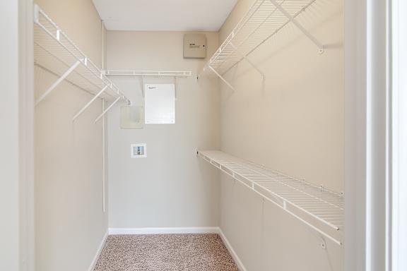 a spacious walk in closet with white rails and shelves at Legacy Apartment Homes in Ridgeland, MS