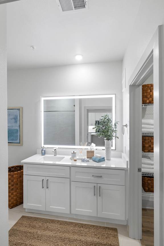 A bathroom with a white vanity and a brown rug.