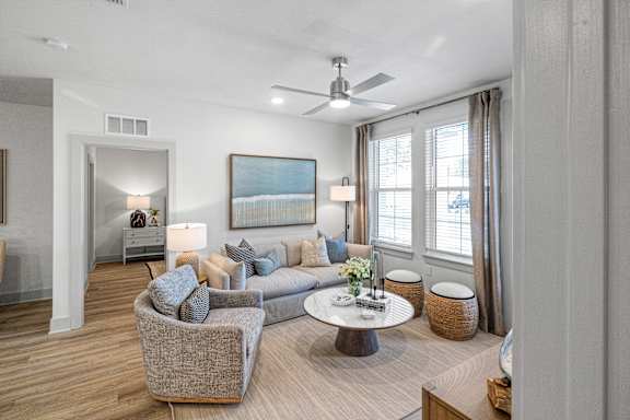 A modern living room with a grey couch, a coffee table, and a painting on the wall.