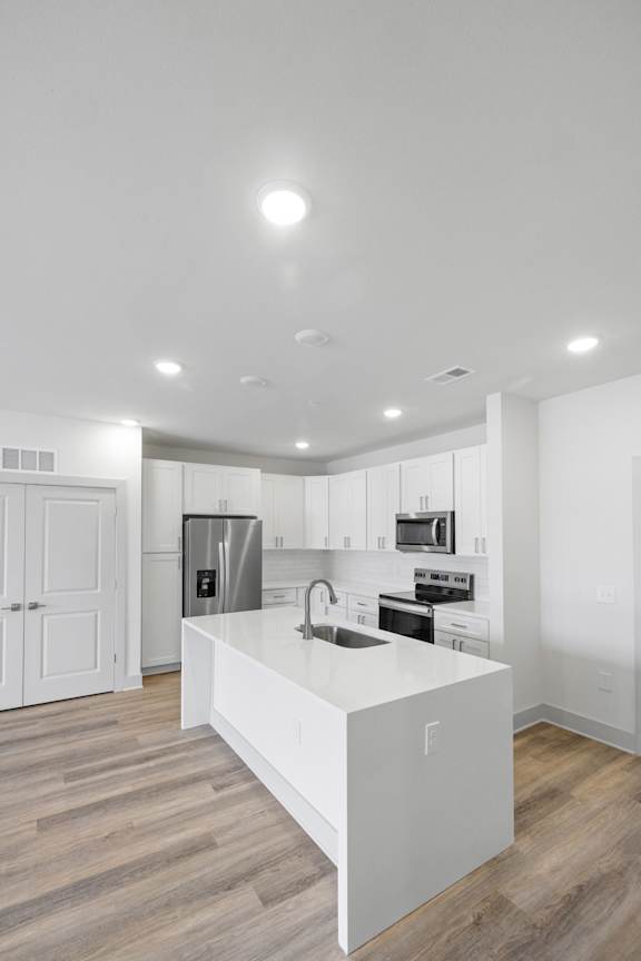 A modern kitchen with a white island and stainless steel appliances.