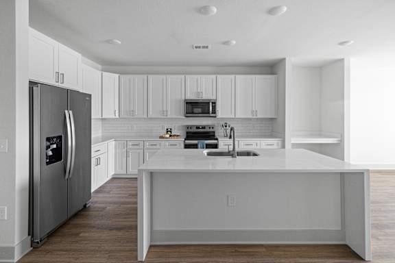 A modern kitchen with white cabinets and a large island.