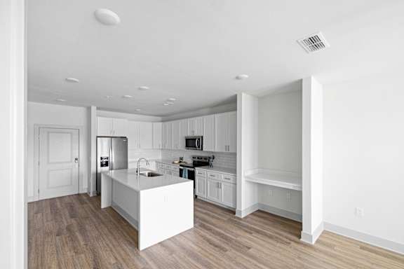A modern kitchen with white cabinets and a white island.
