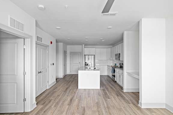 A white kitchen with a wooden floor and a white island in the middle.
