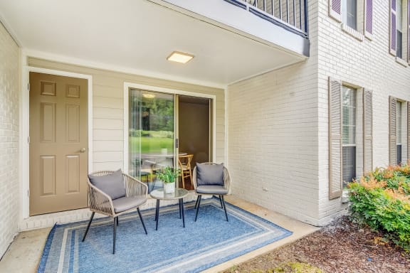 a patio with two chairs and a table on a blue rug  at Cambridge Station Apartment Homes, Mississippi