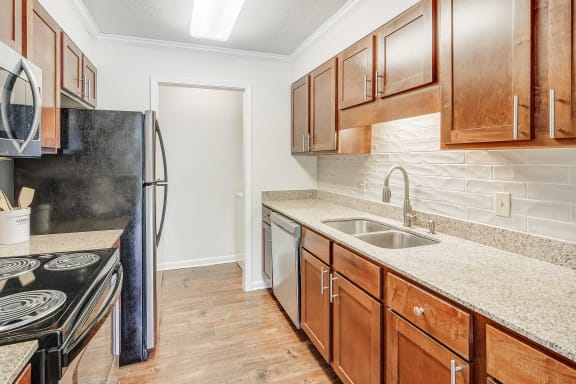 a kitchen with wood cabinets and granite counter tops and a stainless steel refrigerator  at Cambridge Station Apartment Homes, Oxford, 38655