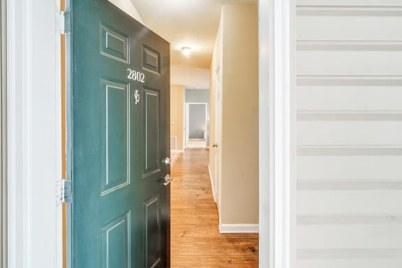 a view of a hallway with a green door and a hall way with a staircase at The Vineyard of Olive Branch Apartment Homes in Mississippi  38654
