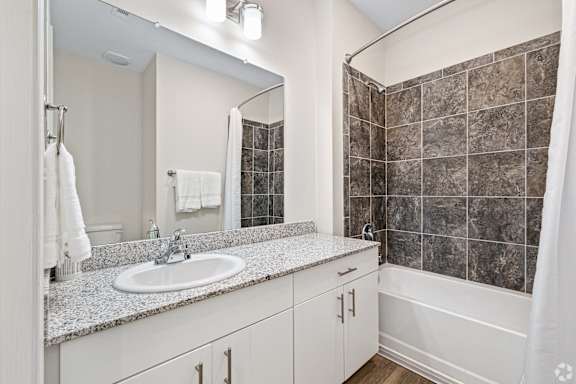 a bathroom with a sink and a shower and a mirror at The Met Apartment Homes, Hattiesburg, MS