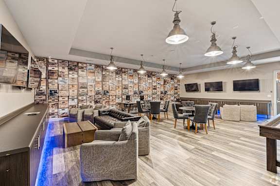a lounge area with couches chairs and tables and a bar at The Met Apartment Homes, Hattiesburg
