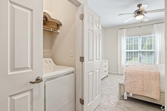 a laundry room with a closet and a bed and a ceiling fan at The Met Apartment Homes, Hattiesburg, MS
