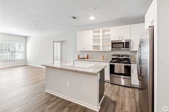 a renovated kitchen with stainless steel appliances and white cabinets at The Met Apartment Homes, Hattiesburg, MS, 39402