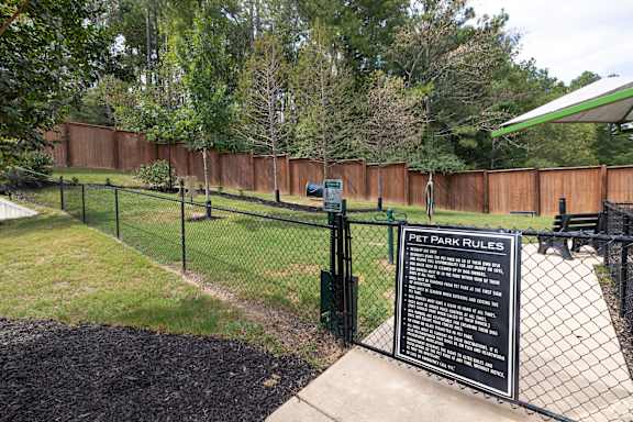 a dog park with a sign on a chain link fence at The Met Apartment Homes, Hattiesburg