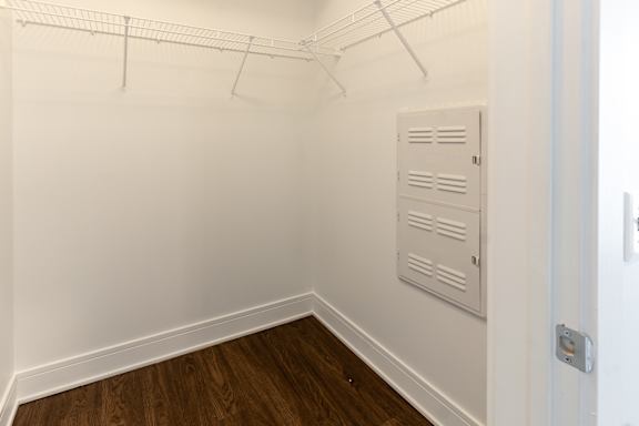 A white closet with a wooden floor and a white door. at The Whit Apartments, Indianapolis, IN