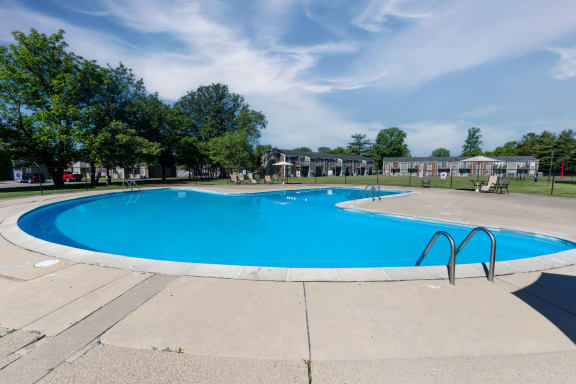 a swimming pool with trees and apartments in the background