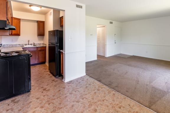an empty kitchen and living room with a black refrigerator