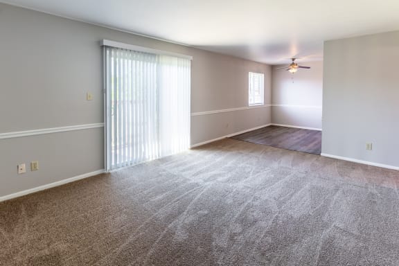 an empty living room with a window and a ceiling fan